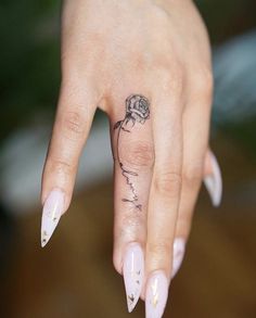 a woman's hand with a rose tattoo on her left thumb and the tip of her finger