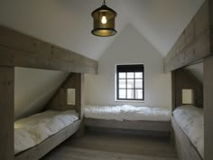 there are two beds in the room with no sheets on them and one has a light hanging from the ceiling