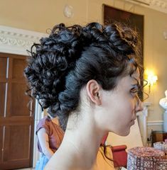 a woman with curly hair standing in front of a cake