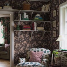 a living room filled with furniture and bookshelves next to a window on a hard wood floor