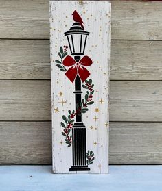 a painted wooden sign with a red bow on it's head and a street light