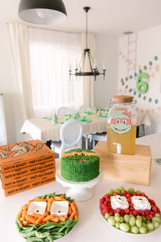 a table topped with cakes covered in frosting next to fruit and veggies