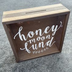 a wooden box with the words honey moon fund written in white on it, sitting on concrete