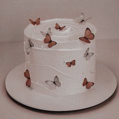 a three tiered cake with butterflies on the icing and frosting, sitting on a white plate