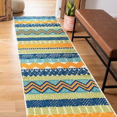 a multicolored rug is on the floor next to a wooden bench and potted plant