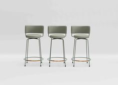 three modern stools with arms and backrests in various colors, one is light green