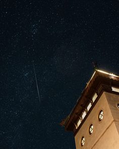 the stars are shining brightly in the night sky above a building with a clock tower