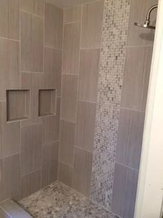 a walk in shower sitting next to a toilet and tiled walls with square niches