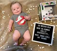 a baby laying on a bed next to a pop box