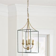 a chandelier with four lights hanging from it's sides in a room