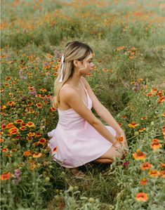 a woman kneeling down in a field of flowers