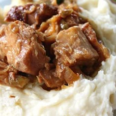 a close up of mashed potatoes with meat and gravy on top in a plate