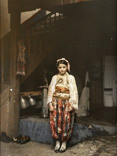 an old photo of a woman standing in front of stairs