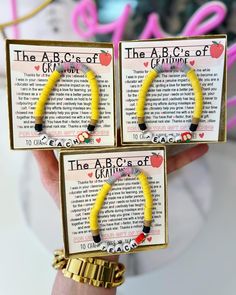 two yellow bracelets with black and red beads are held in front of each other