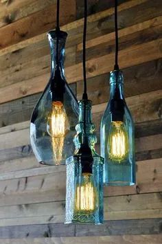 three glass bottles are hanging from the ceiling with light bulbs attached to them, and one is empty