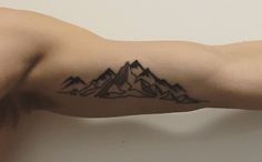 a man's arm with mountains tattoo on the upper part of his arm and shoulder