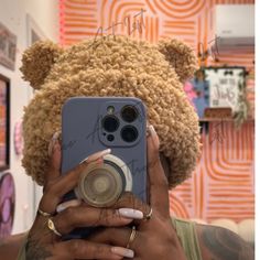 a woman taking a selfie with her cell phone in front of a teddy bear