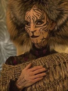 a woman with her face painted like a tiger is holding a large piece of fur