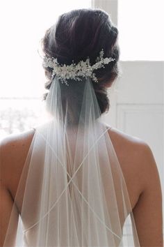 the back of a bride's head wearing a veil with flowers on it,