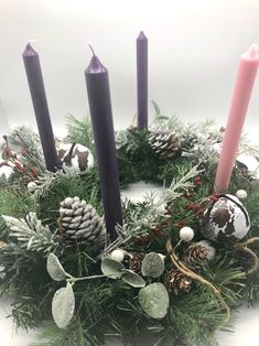 a christmas wreath with candles and decorations on it, sitting in front of a white background