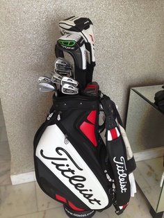 the golf bag is sitting on the floor next to his putter's clubs