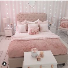 a bedroom with pink bedding and pillows on the headboard is decorated with lights