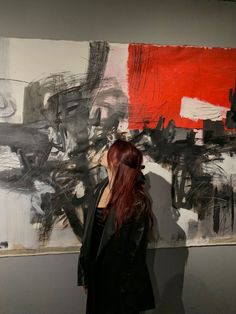 a woman standing in front of a large painting