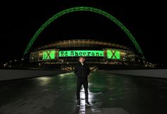 a man standing in front of an arch at the end of a stadium with green lights