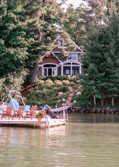 a boat with chairs on it floating in the water next to a house and trees