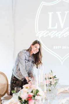 a woman standing in front of a table with flowers and candles