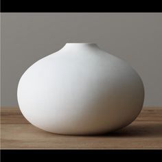 a white vase sitting on top of a wooden table