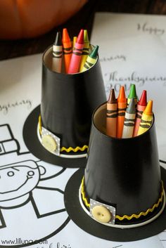 two black cups with crayons in them sitting on top of a paper plate