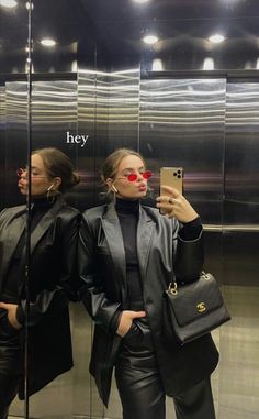 two women standing in front of a mirror taking a selfie with their cell phone