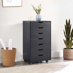 a tall black cabinet with five drawers next to a potted plant