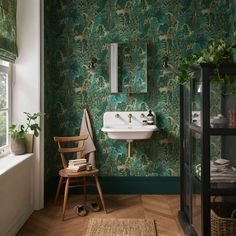 a bathroom with green wallpaper and wooden flooring