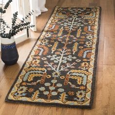 a rug on the floor with a plant in front of it and a vase next to it