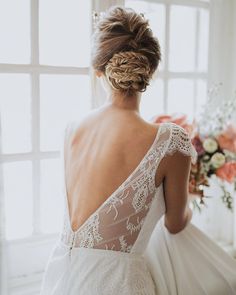 the back of a bride's dress as she stands in front of a window