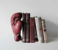 a pair of boxing gloves sitting on top of three bookends next to each other