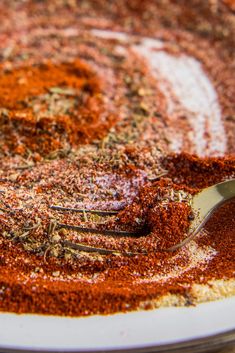 a fork is stuck in the ground on a plate with red seasoning sprinkles