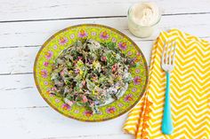 paleo caesar salad dressing on a yellow and white plate next to a blue fork