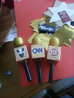 three microphones sitting on top of a red table next to some gold and black stickers