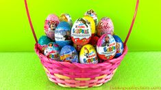 a basket filled with lots of colorful decorated eggs on top of a green table next to a wall