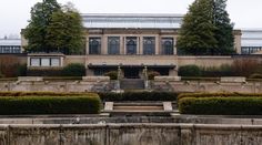 a large building with lots of trees and bushes around it's front entrance area