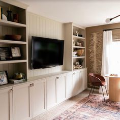 a living room filled with furniture and a flat screen tv on top of a entertainment center