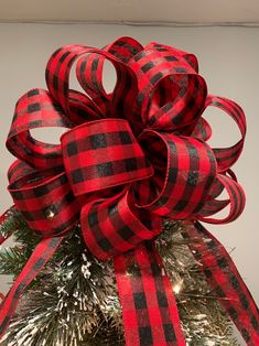 a red and black bow on top of a christmas tree