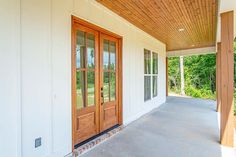 an empty porch with wooden doors and windows