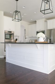 a kitchen with white cabinets and black counter tops, an island in front of the stove