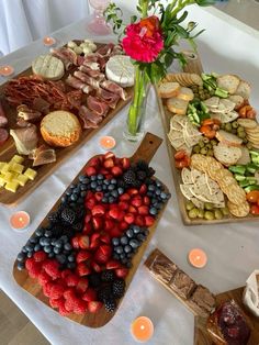 a table topped with trays of food next to candles and plates filled with fruit