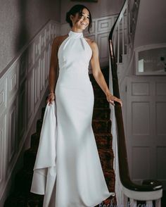 a woman in a white dress standing on some stairs