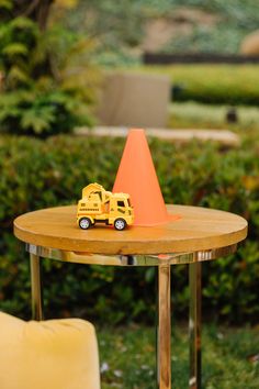 a toy truck is sitting on top of a table with an orange cone over it